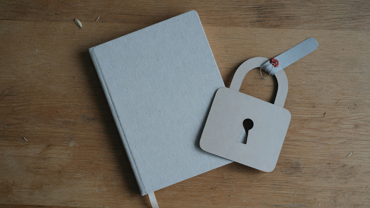 Buku tertutup dan gembok kertas di atas meja kayu